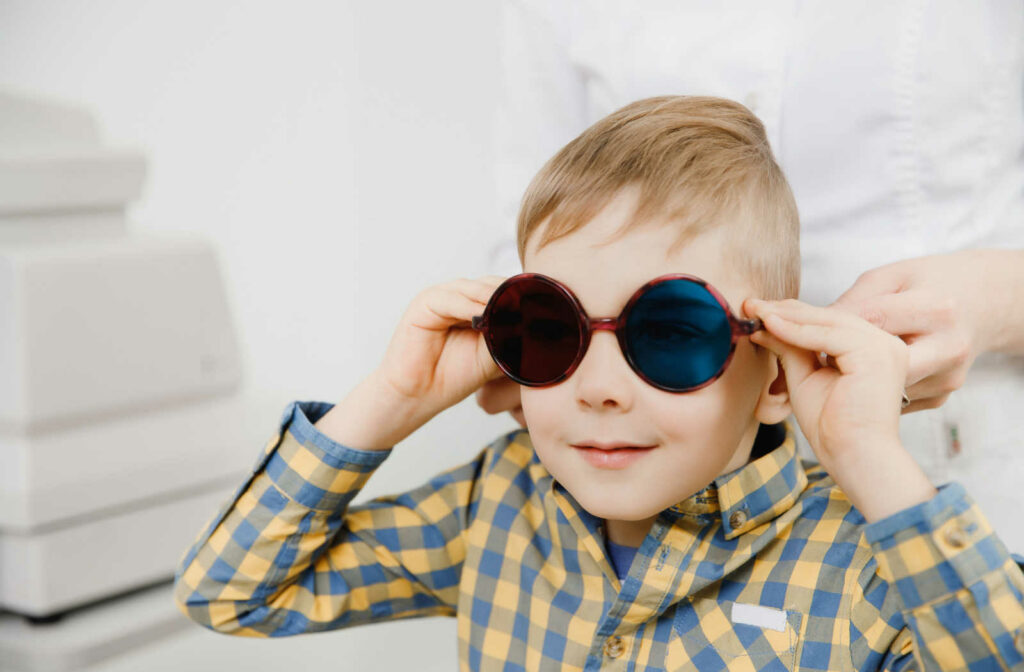 A young boy wearing glasses with a blue lens in the left eye and a red lens in the right to take color vision test.