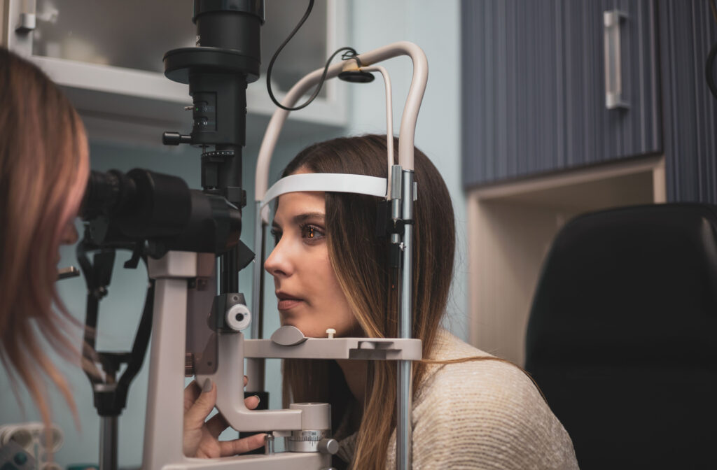 A young woman leaning towards medical optical equipment about to have an eye exam.