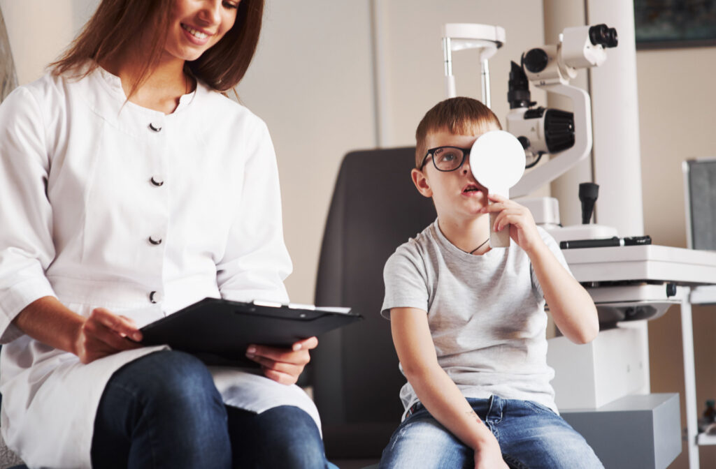 A young boy holding a white occluder during a visual acuity test.