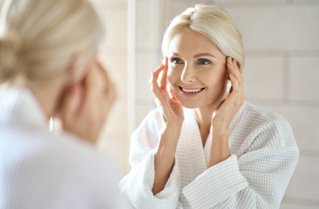 A mature patient admiring their healthy and youthful-looking skin in the mirror.