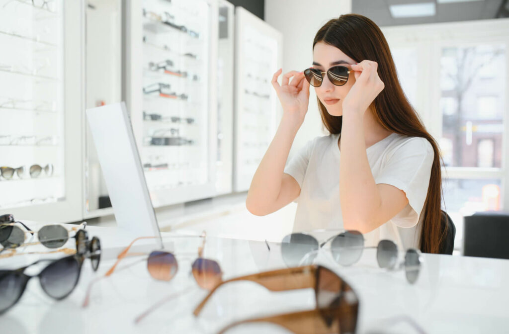 A young adult trying on a pair of polarized sunglasses in front of a small display trying to decide if they're worth it.