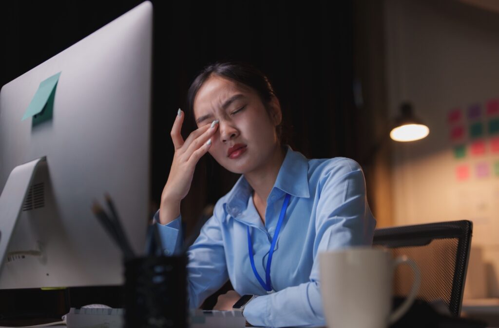 Woman rubbing her tired eyes at her desktop computer.
