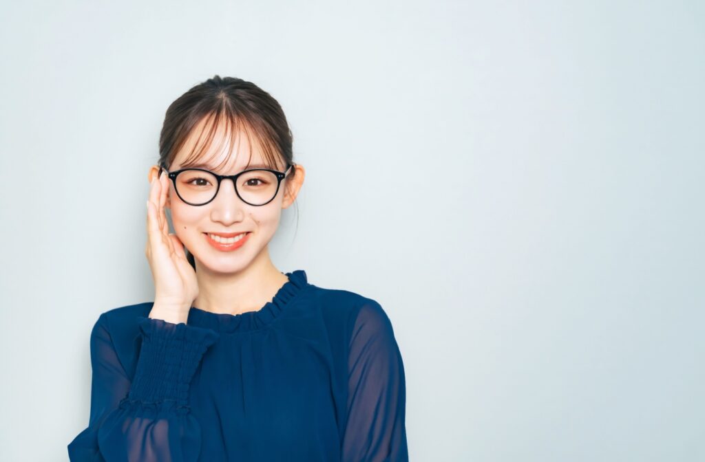 Young woman adjusting her eyeglasses, showing proper frame positioning for clear and comfortable vision.