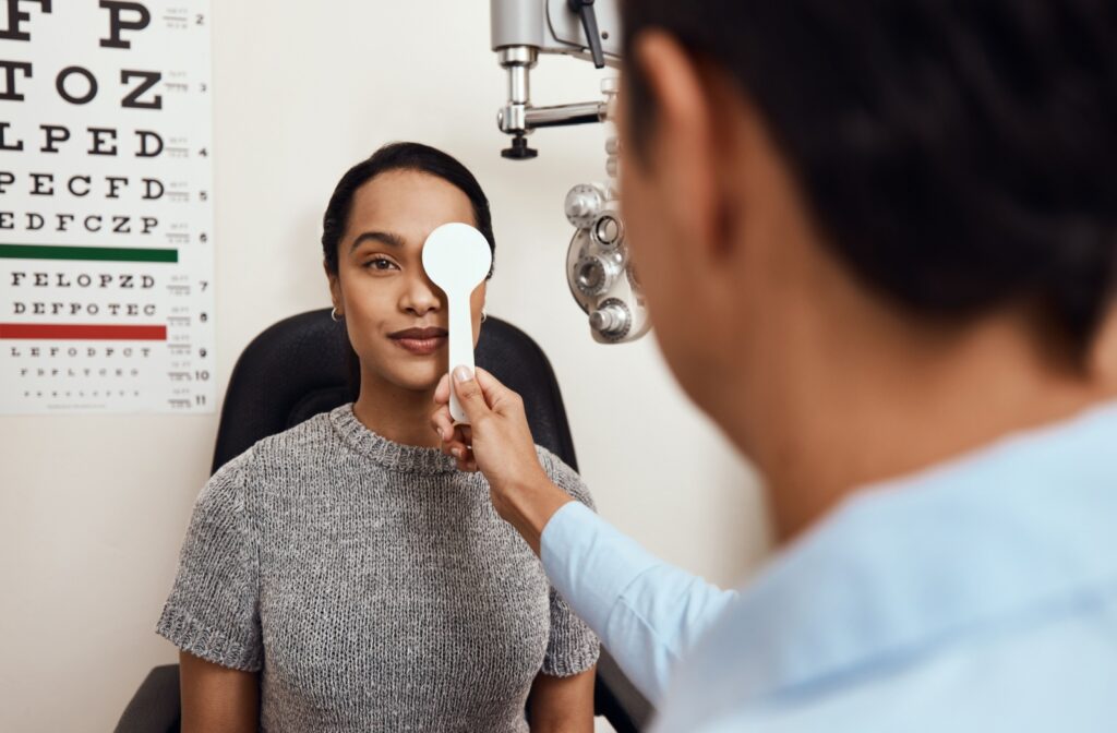 Optometrist performing a vision test with an eye occluder during a comprehensive eye exam.
